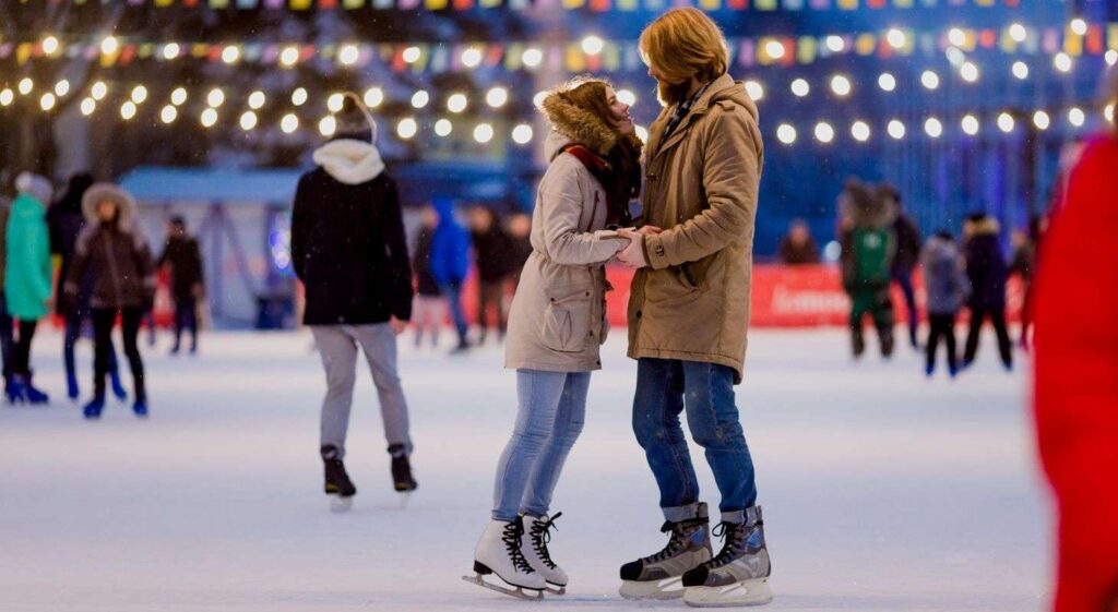 Young couple ice skating on open air rink in Vermont.