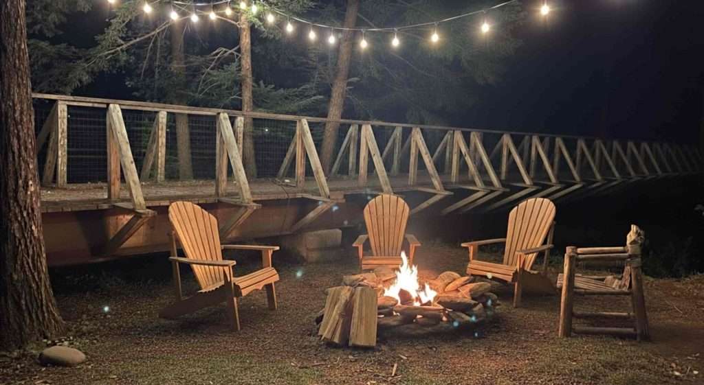 Wooden chairs around a firepit at night at Warren Lodge in Vermont