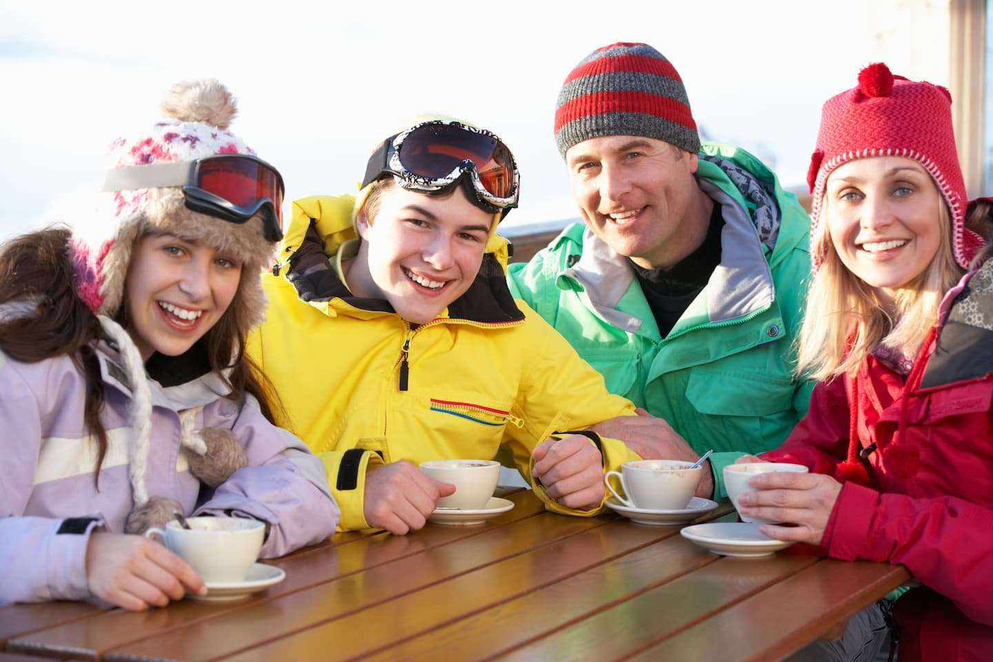 A family drinking hot chocolate around a table at an outdoor skating rink in Vermont