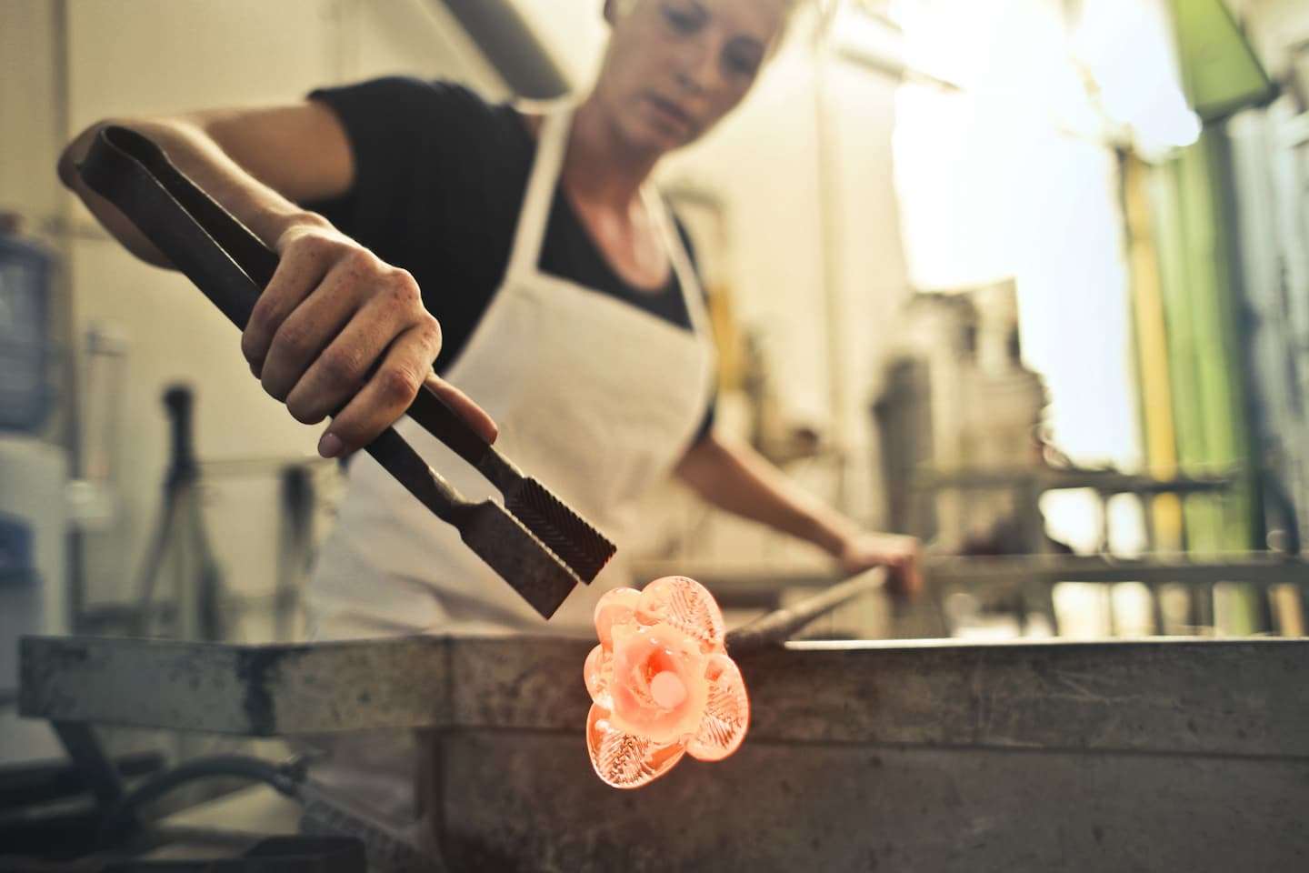 A woman at a Vermont glass-blowing studio crafting a flower